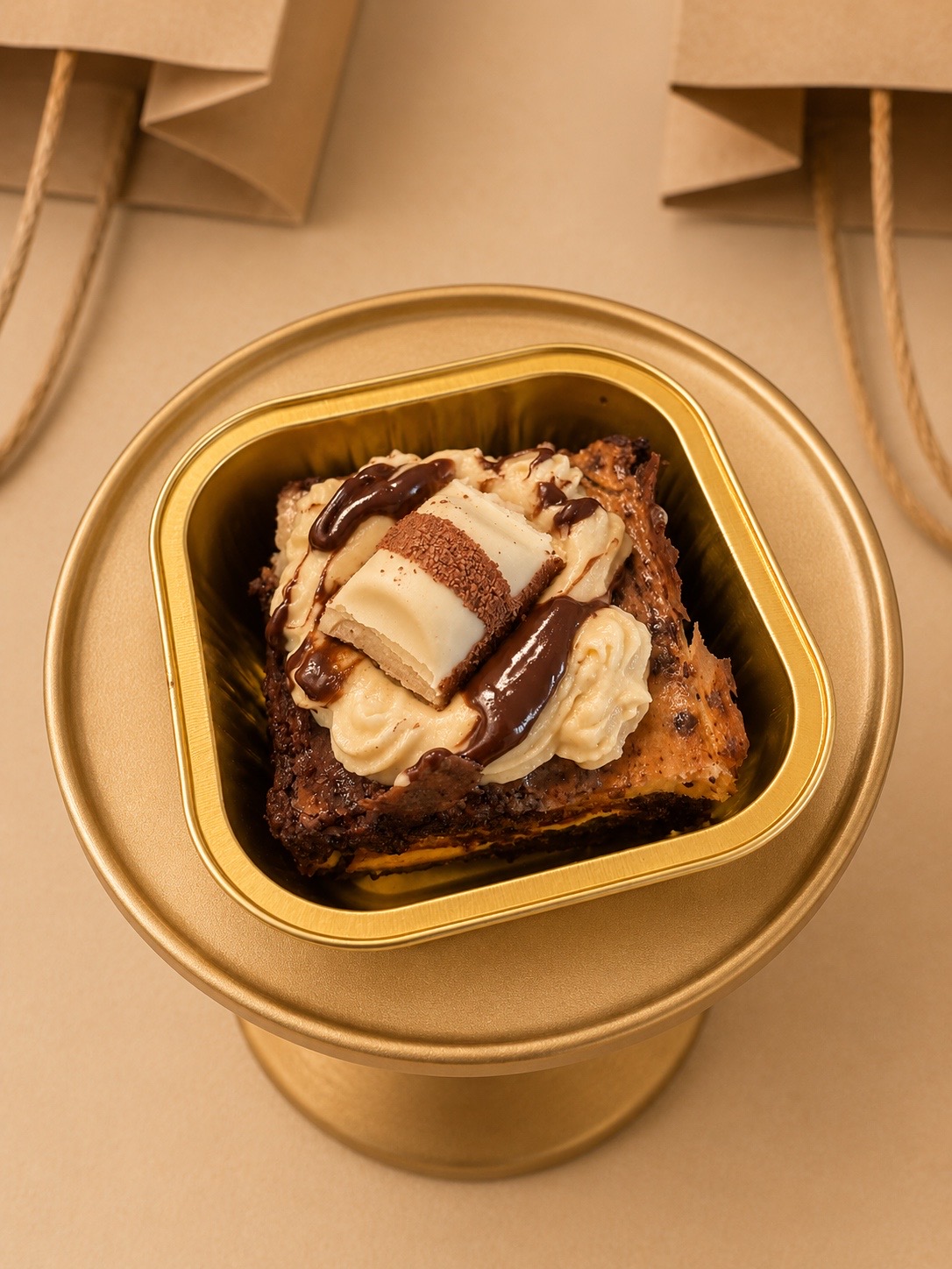 Kinder cheesecake brownie in a gold tray with paper bags behind
